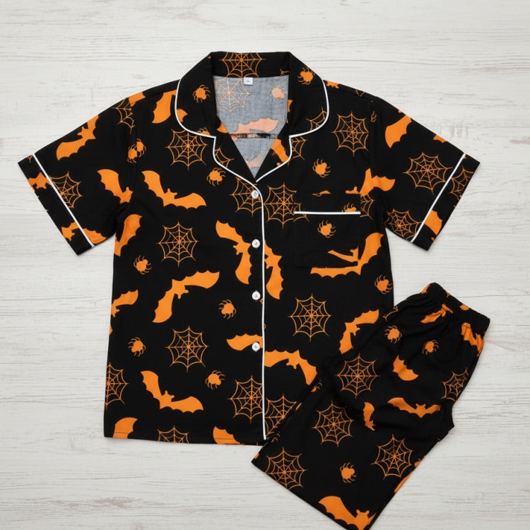 Halloween-themed pajama set with orange patterns on a black background.