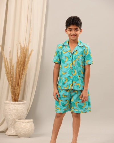 Child wearing a turquoise pajama set with banana pattern against a neutral background