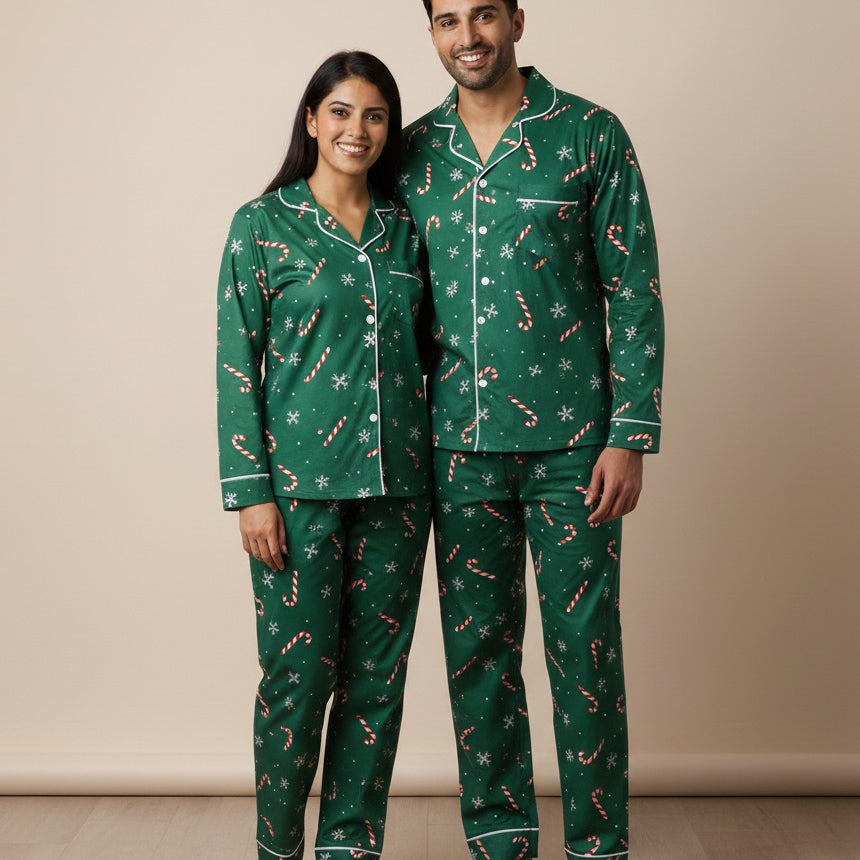 Man and woman wearing matching green pajama sets with candy cane pattern on a beige background