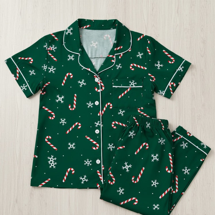 Green pajama set with candy cane and snowflake pattern on a light wooden surface