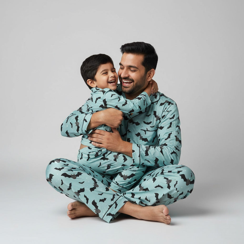 Father and son wearing flying bats matching pajamas, Halloween bat-themed coordinated nightwear.