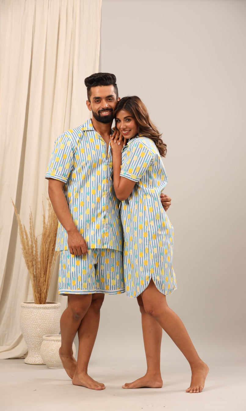 Husband and wife wearing matching blue and yellow striped pajama sets against a neutral background.