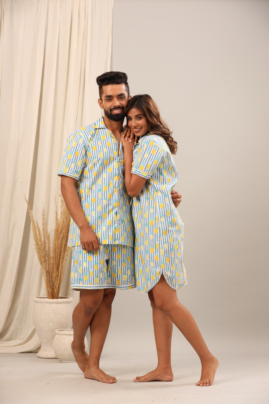 Husband and wife wearing matching blue and yellow striped pajama sets against a neutral background.