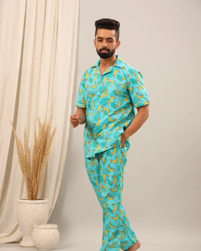 Man wearing a turquoise pajama set with banana pattern against a neutral background