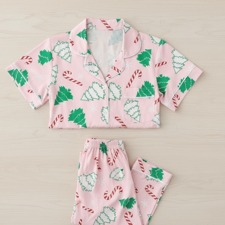 Pink pajama set with Christmas tree and candy cane patterns on a beige background