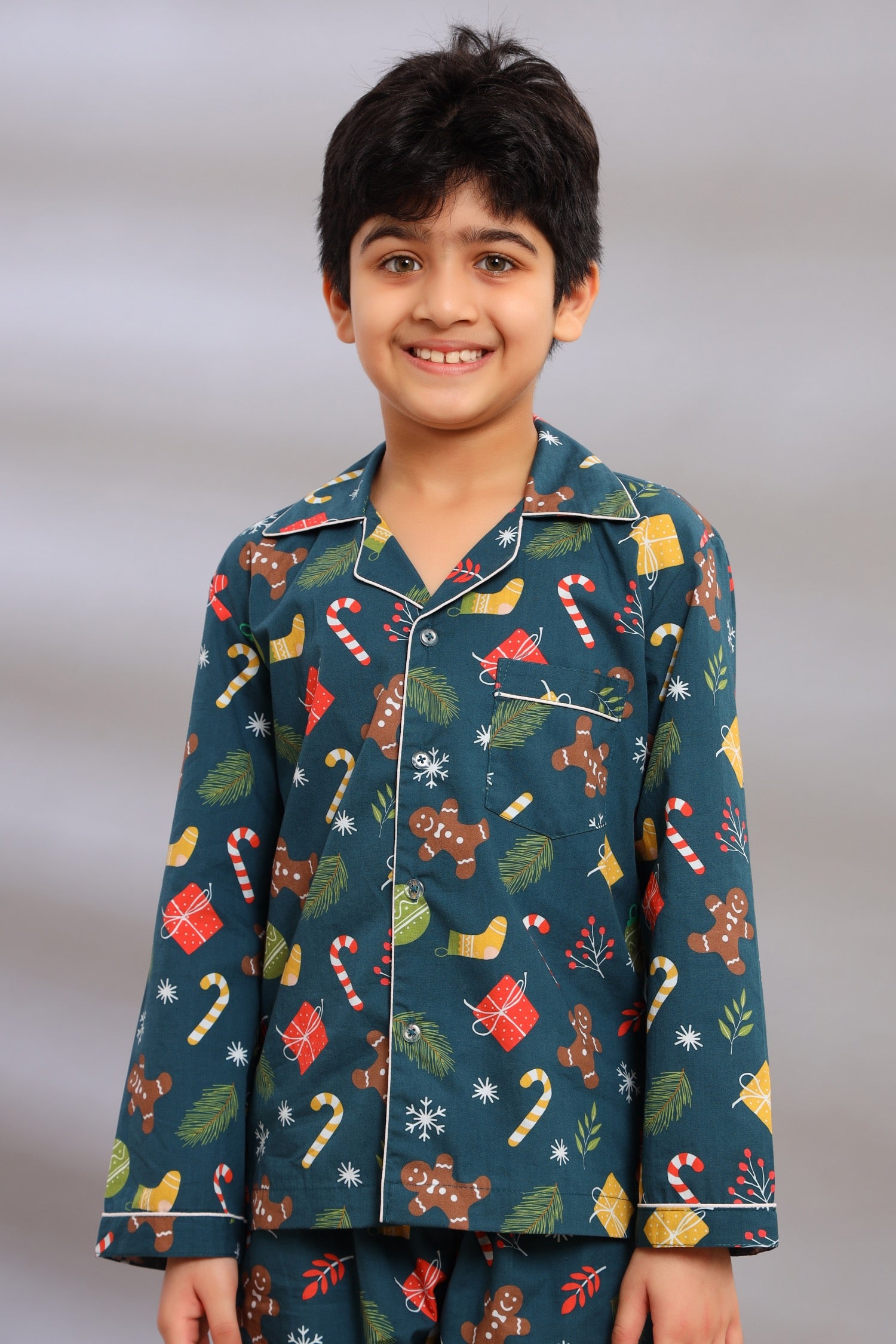 Boy wearing a festive Christmas nightwear set with candy cane, gingerbread man, and Christmas presents