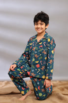 Boy wearing festive Christmas pajamas with a pattern of Christmas elements on a neutral background