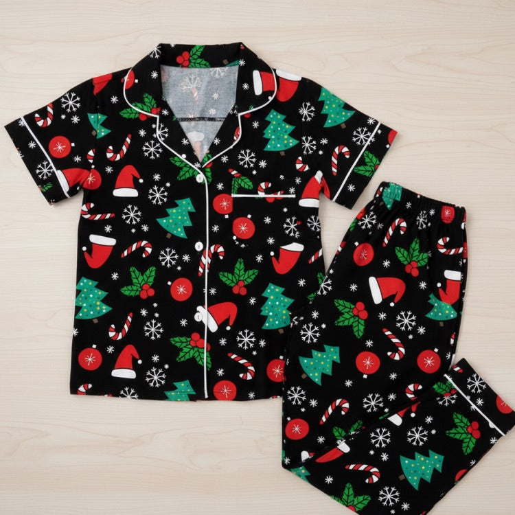 Christmas-themed pajama set with black background featuring red, green, and white patterns on a light wooden surface.