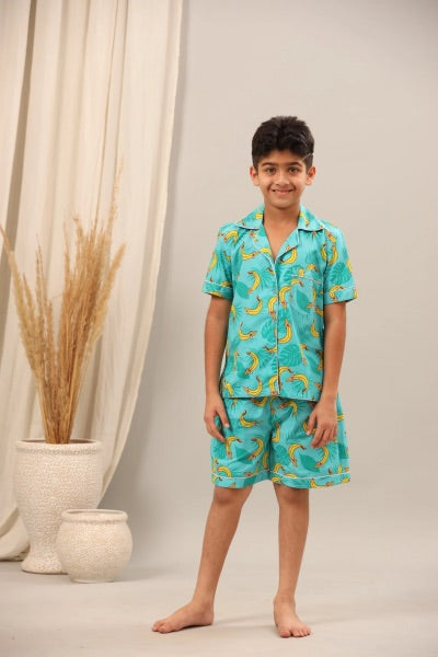 Child wearing a turquoise pajama set with banana pattern against a neutral background