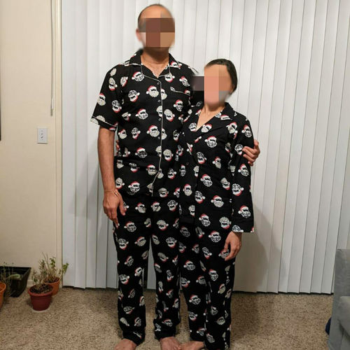 Couple wearing matching black Christmas pajama sets with a pattern in a room.