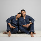 Matching couple pajamas in deep navy and grey striped cotton.