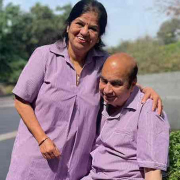 Two elderly people in matching purple pajamas standing outdoors