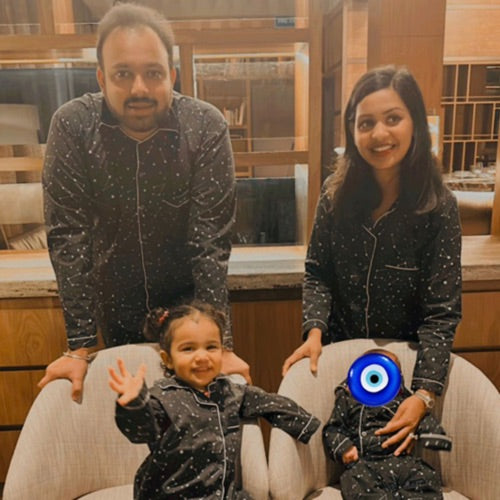 Family of three wearing matching night suits with black space print and stars