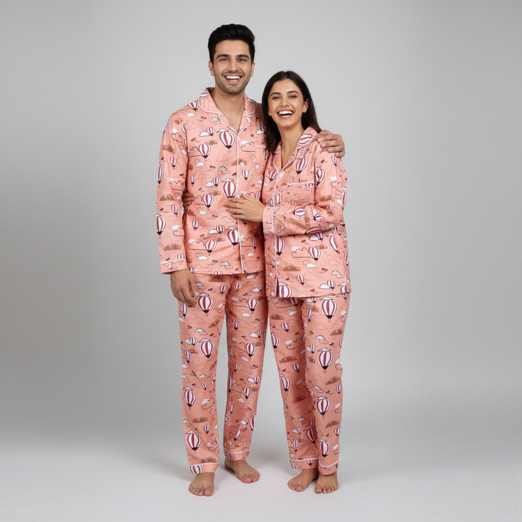 Couple wearing hot air balloon in clouds matching pajamas, soft sky-themed coordinated nightwear.