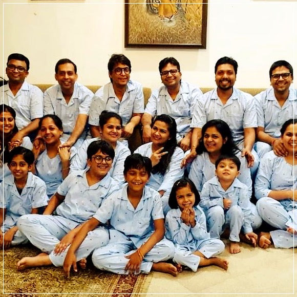 Group of people in matching light blue pj set posing for a photo indoors.