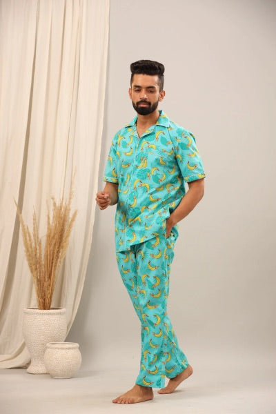 Man wearing a turquoise pajama set with banana pattern against a neutral background