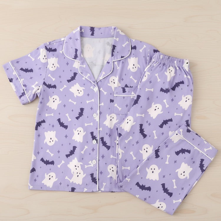 Purple pajama set with ghost, bat, and bone pattern on a beige background