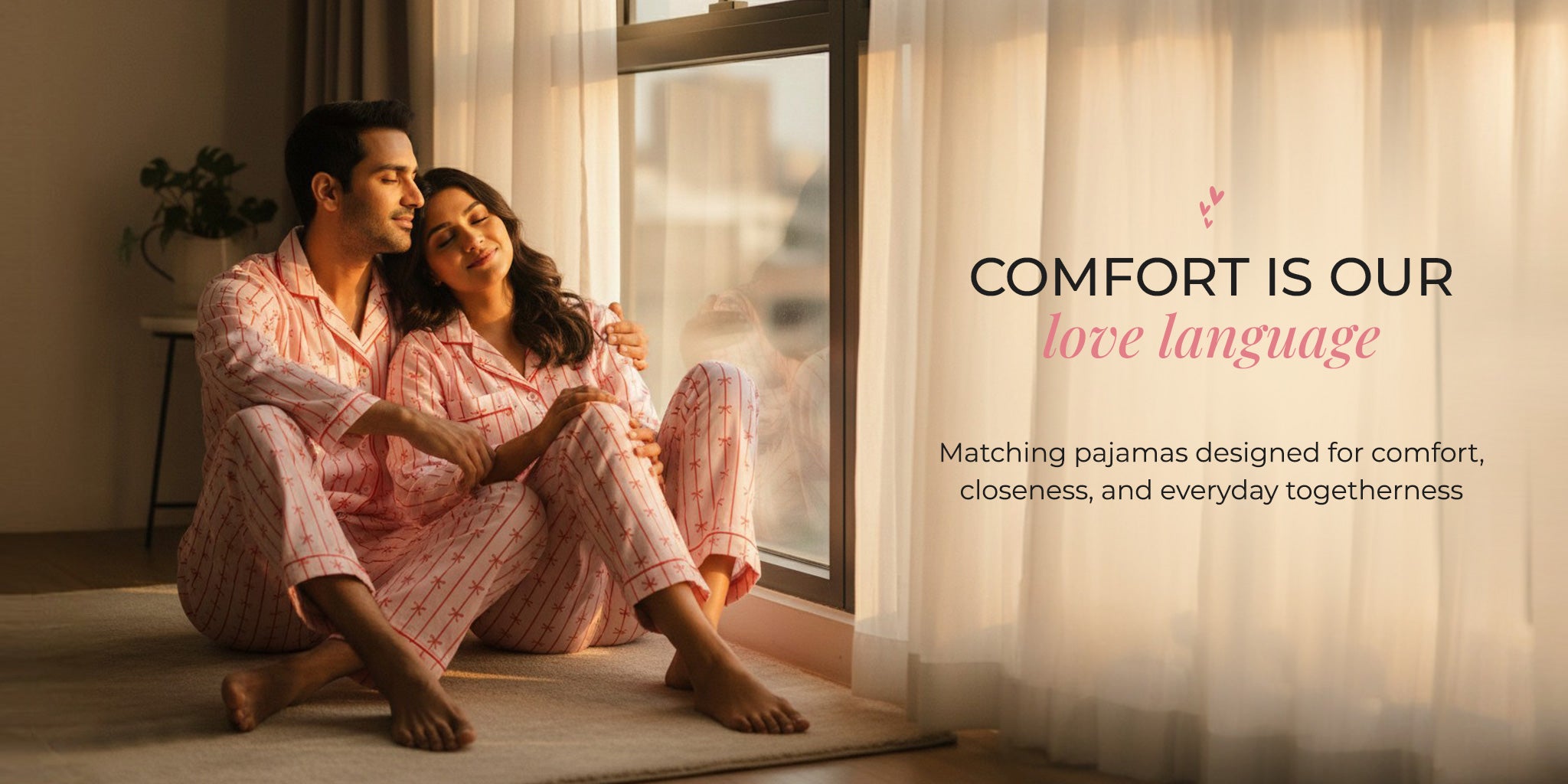 Couple in matching pajamas sitting by a window