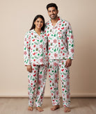 Man and woman wearing matching Christmas-themed pajamas against a beige background